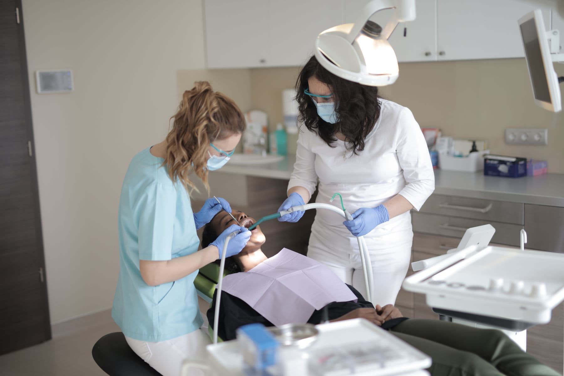 Two dentists examining a patient's teeth in a modern clinic