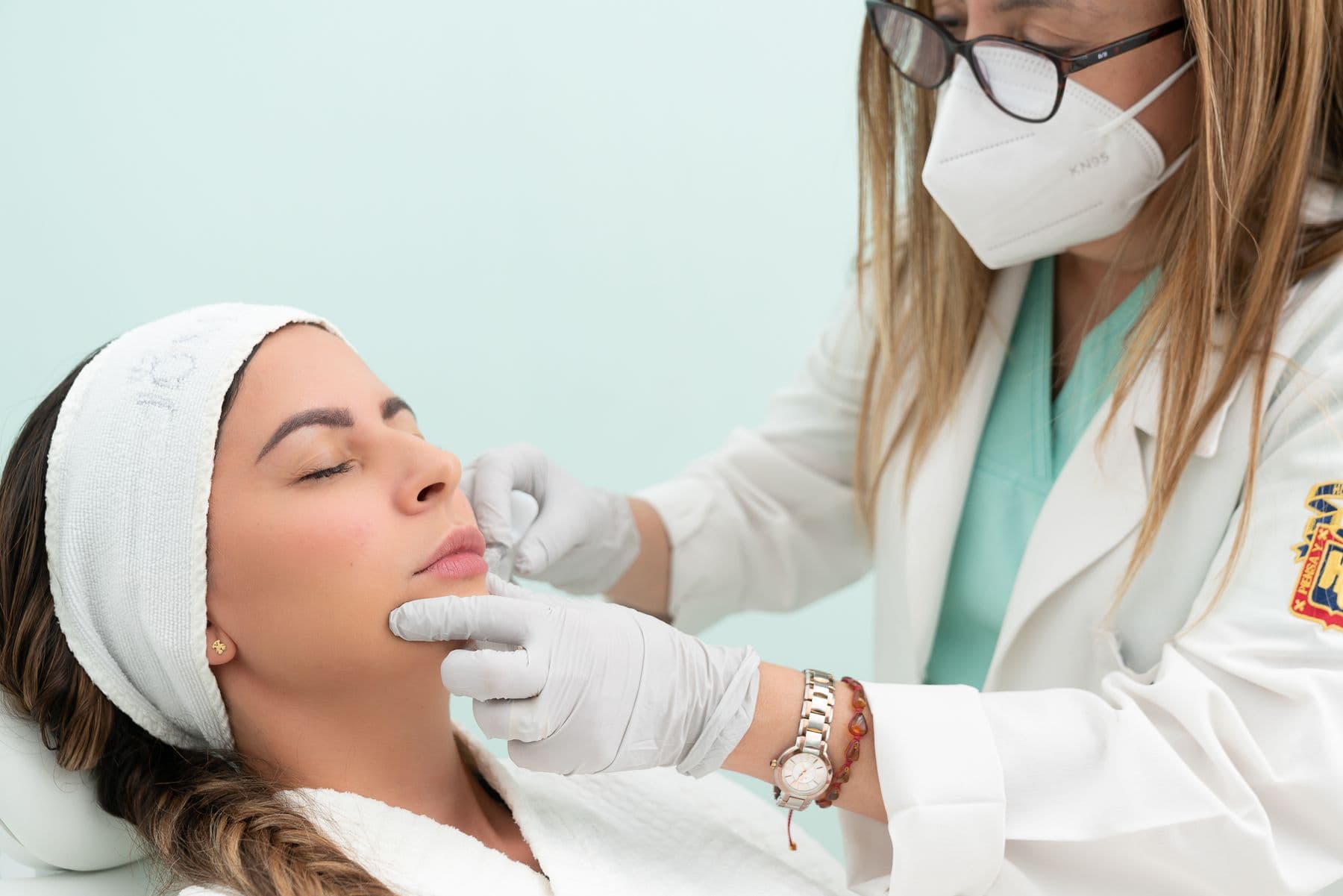 A doctor in a mask treating a patient's face in a clinic