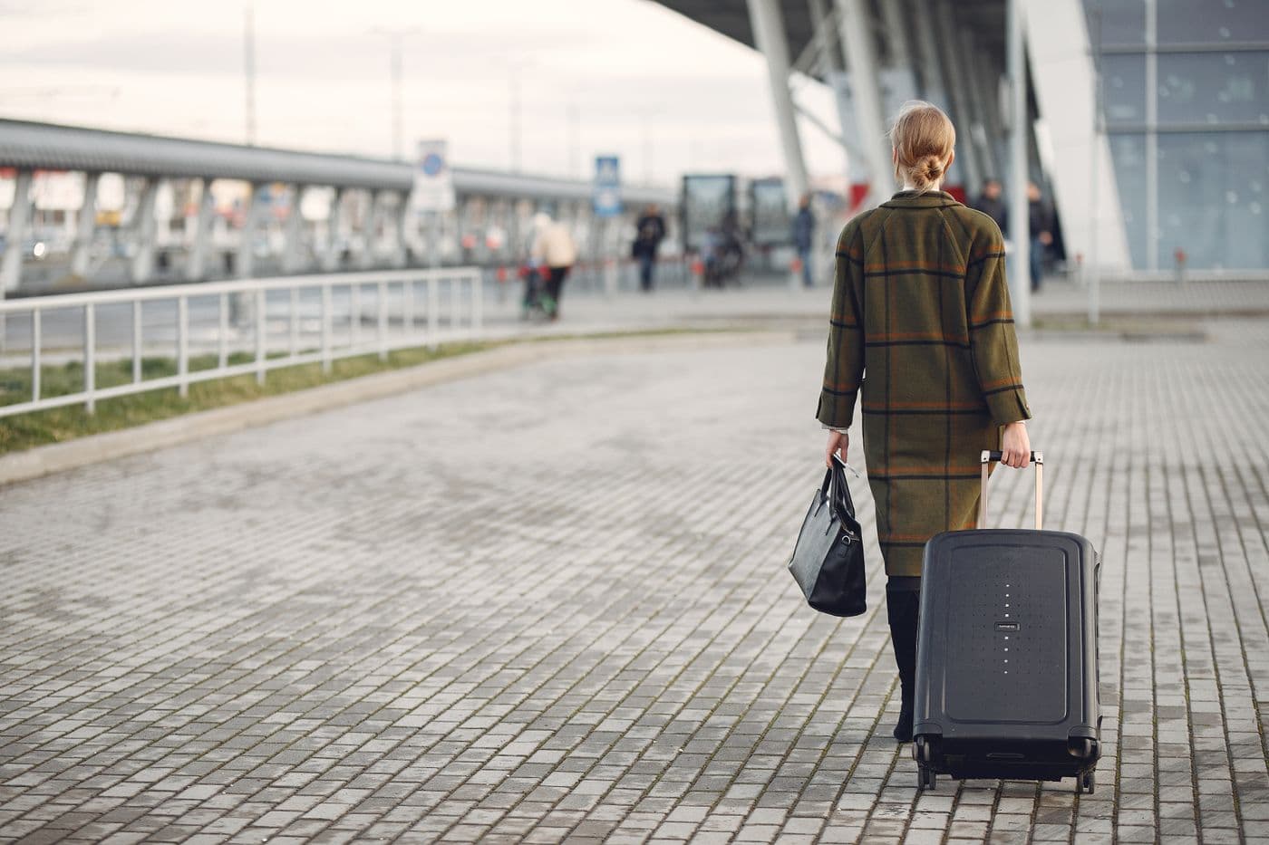 A traveler pulling a suitcase outside an airport terminal